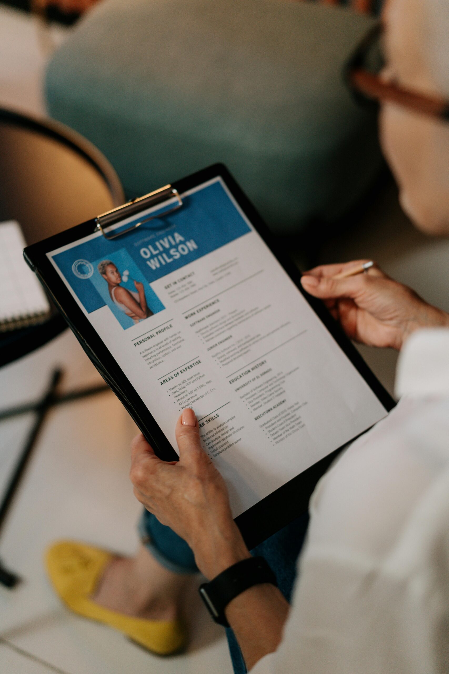 An HR professional reviews a resume on a clipboard during an office meeting.